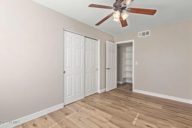 an empty room with closet and a chandelier fan