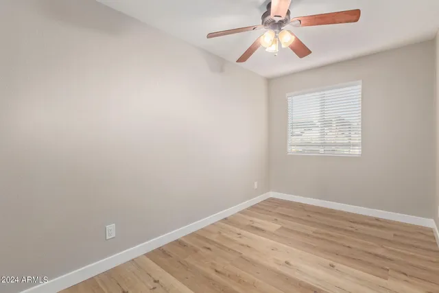 a view of an empty room with window and wooden floor