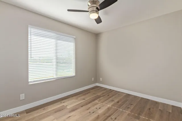 a view of empty room with wooden floor and fan