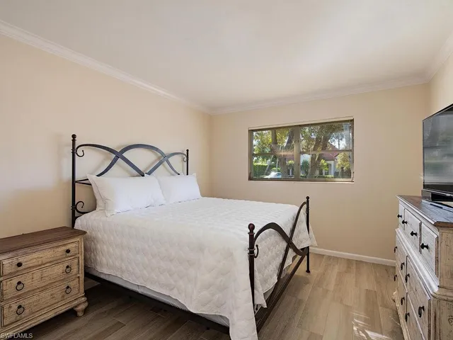 a bedroom with a bed and a flat tv screen on the dresser