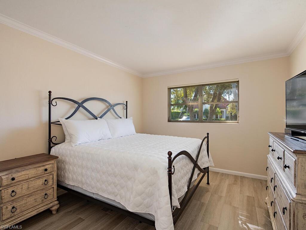 271 1st Avenue South Naples, FL 34102 - Photo 11 of 14 a bedroom with a bed and a flat tv screen on the dresser