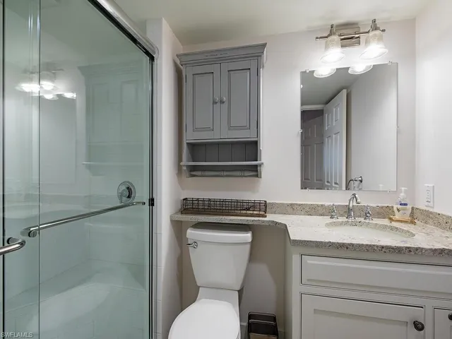 a bathroom with a granite countertop toilet sink and mirror