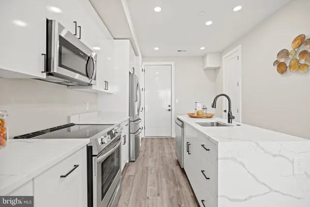 a kitchen with white cabinets appliances and sink