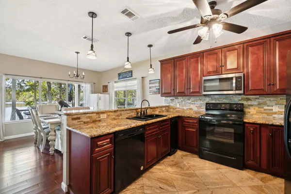 a kitchen with granite countertop a sink a counter space appliances and cabinets