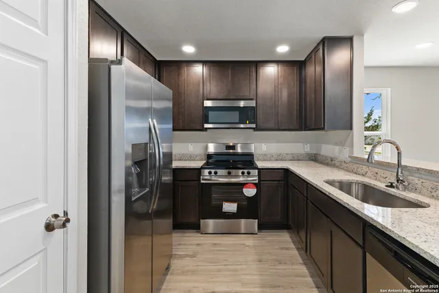 a kitchen with stainless steel appliances granite countertop a refrigerator a sink and a stove