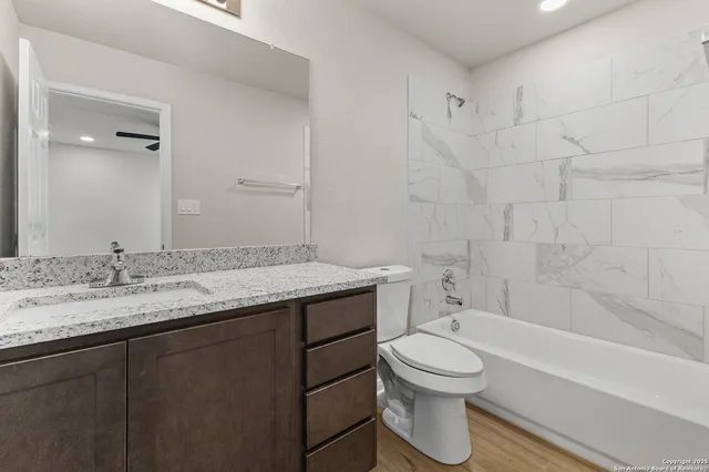 a bathroom with a granite countertop toilet a sink and a bathtub