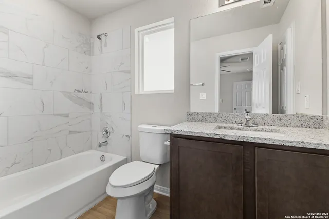 a bathroom with a granite countertop toilet a sink and a bathtub