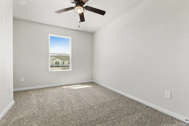 an empty room with a window and a ceiling fan