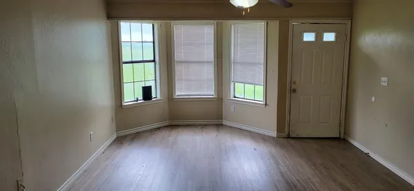an empty room with wooden floor and windows