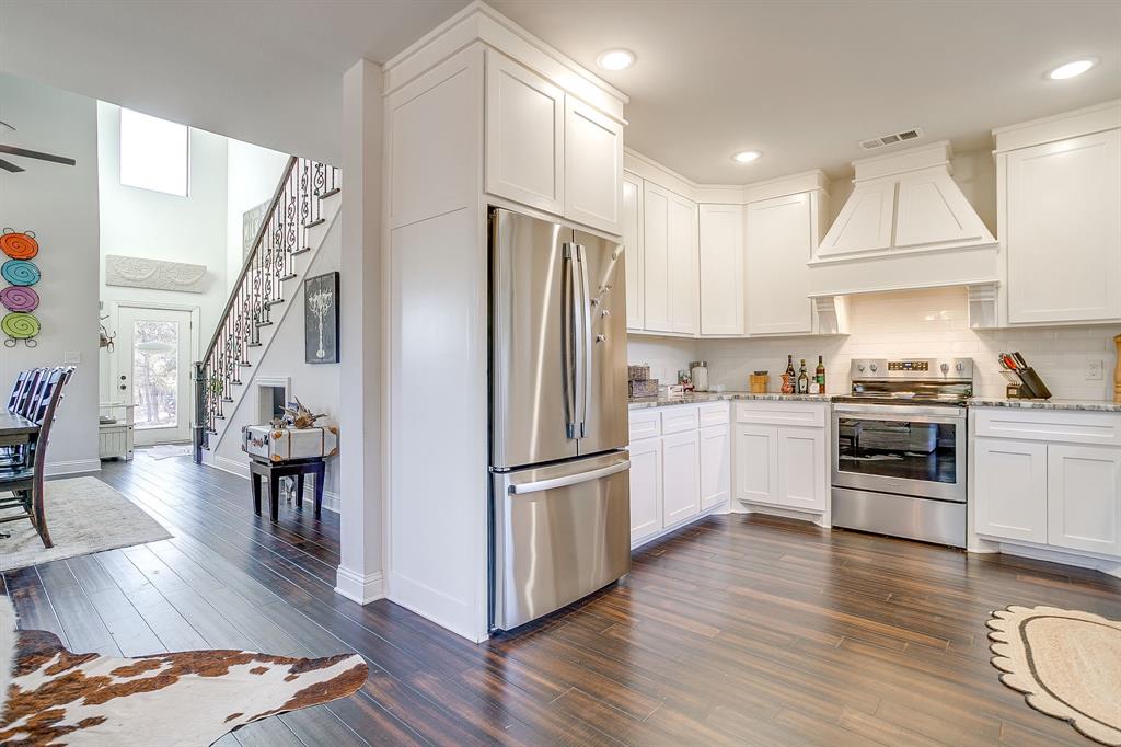 4920 Shining Star Trail Rio Vista, TX 76093 - Photo 18 of 40 a kitchen with granite countertop a refrigerator a stove a sink and a dining table with wooden floor