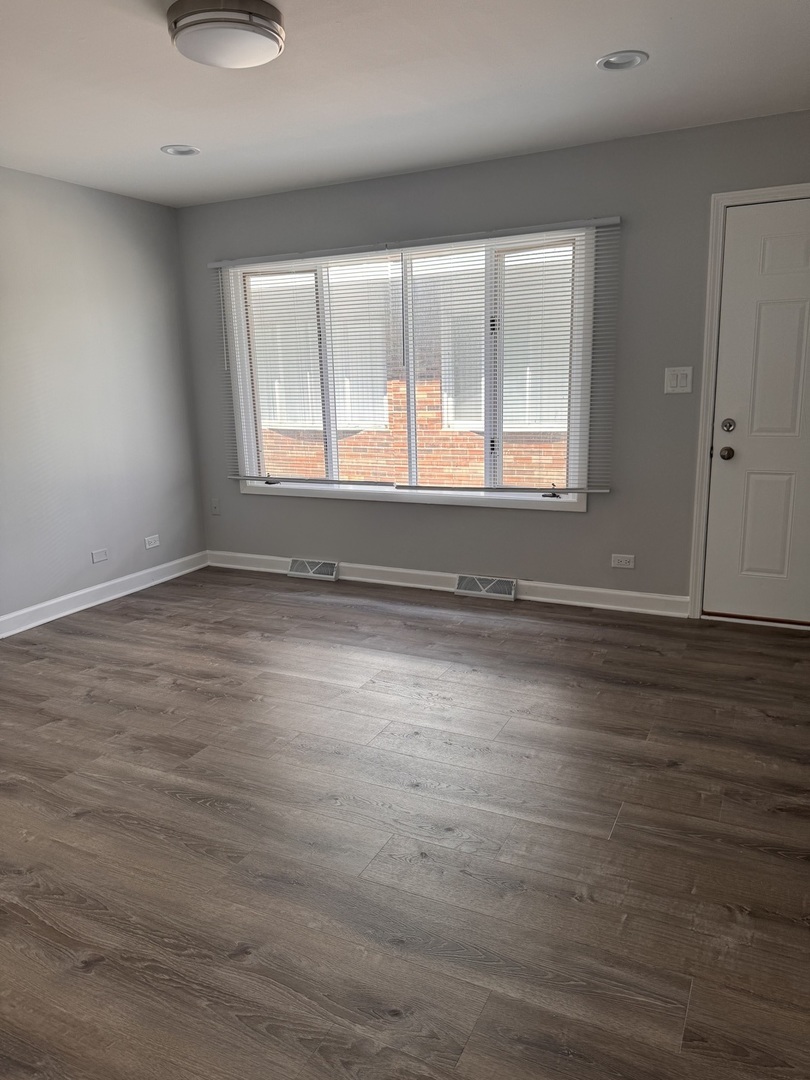 336 Lilac Lane, Unit H Elgin, IL 60123 - Photo 2 of 16 an empty room with wooden floor and windows