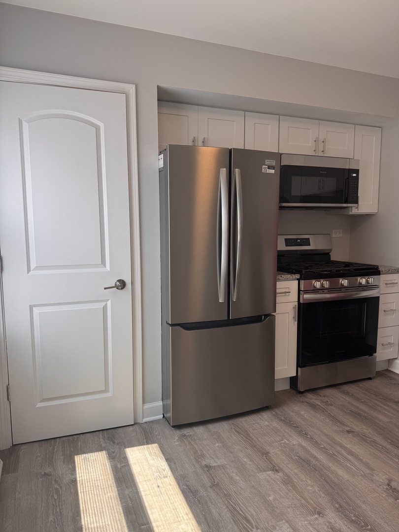 336 Lilac Lane, Unit H Elgin, IL 60123 - Photo 3 of 16 a kitchen with stainless steel appliances a refrigerator stove and microwave