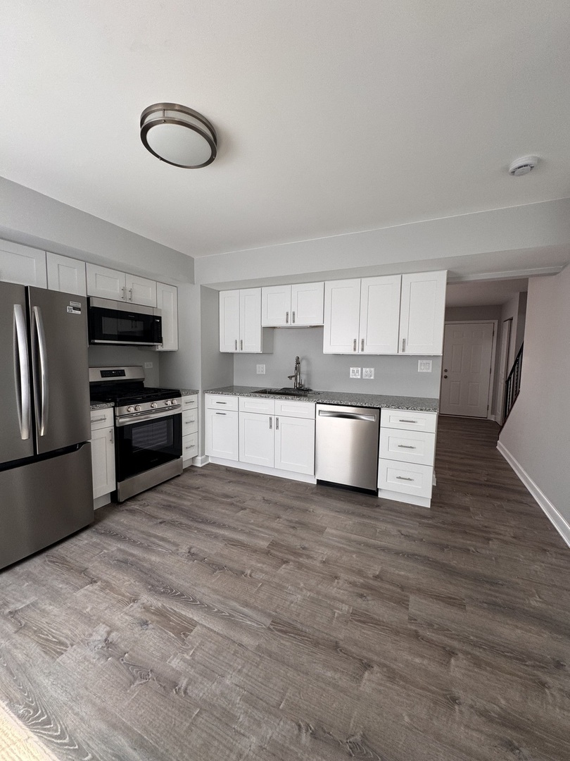 336 Lilac Lane, Unit H Elgin, IL 60123 - Photo 4 of 16 a kitchen with granite countertop a refrigerator and a sink