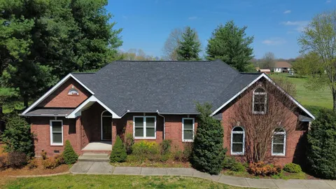 a view of a house with a big yard and potted plants and large trees