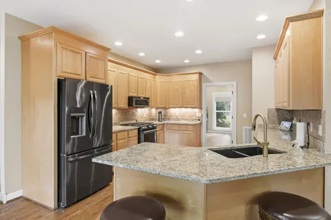 a kitchen with granite countertop white cabinets and stainless steel appliances