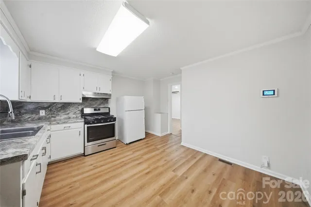 a kitchen with granite countertop a refrigerator stove top oven and sink