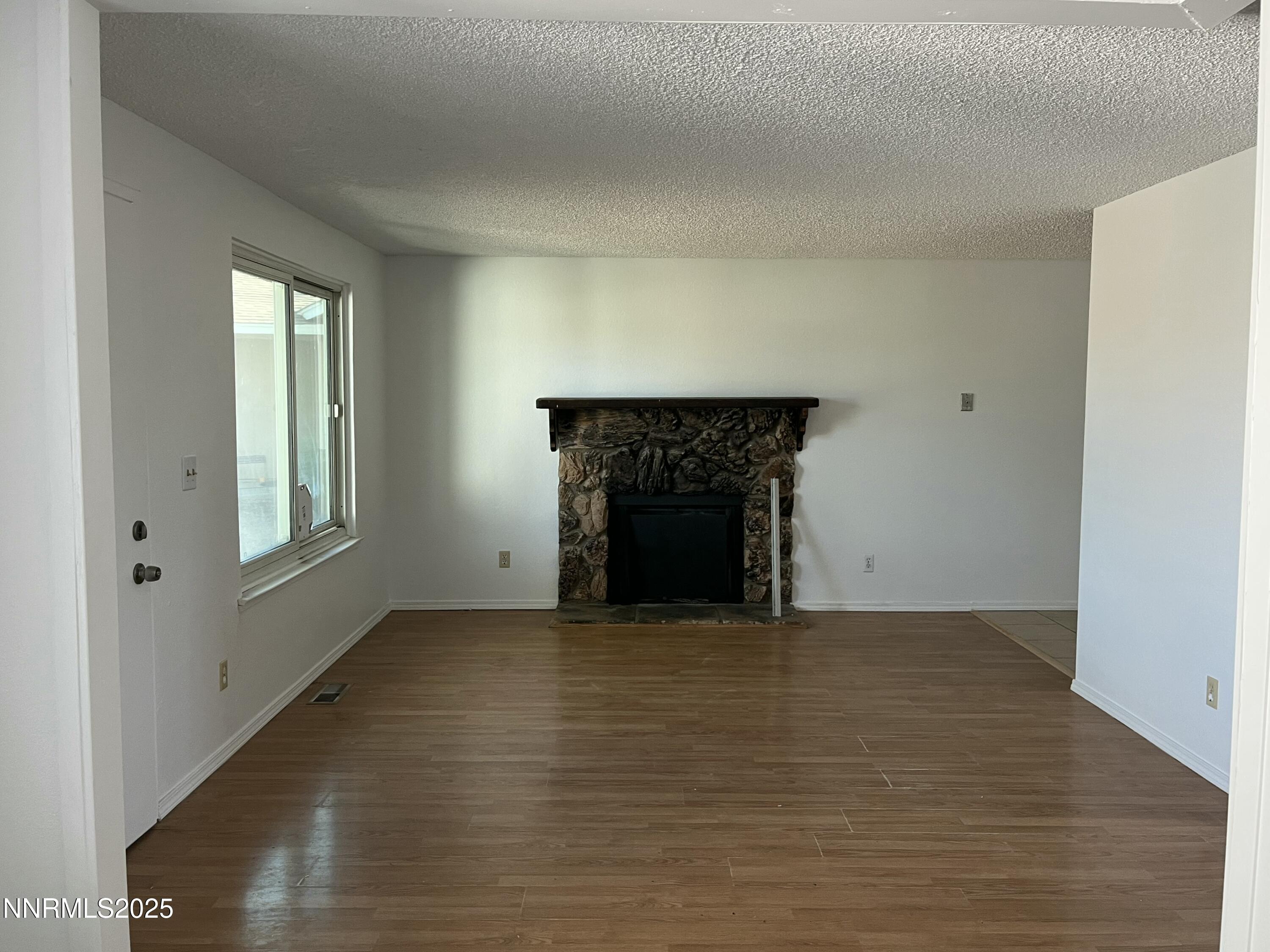 11019 Bornite Court Reno, NV 89506 - Photo 14 of 30 a view of empty room with wooden floor and fireplace