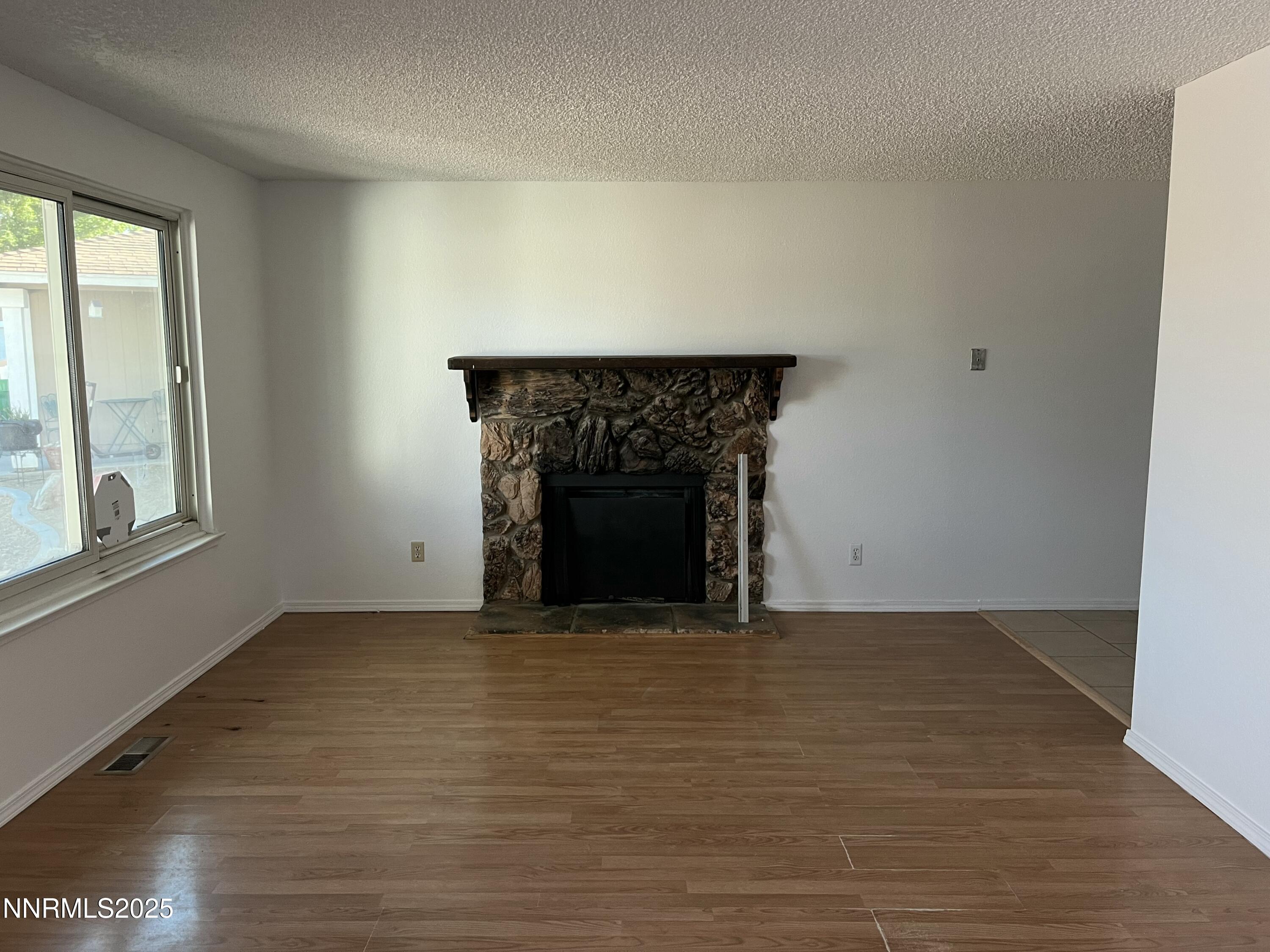11019 Bornite Court Reno, NV 89506 - Photo 21 of 30 a view of empty room with wooden floor and a fireplace