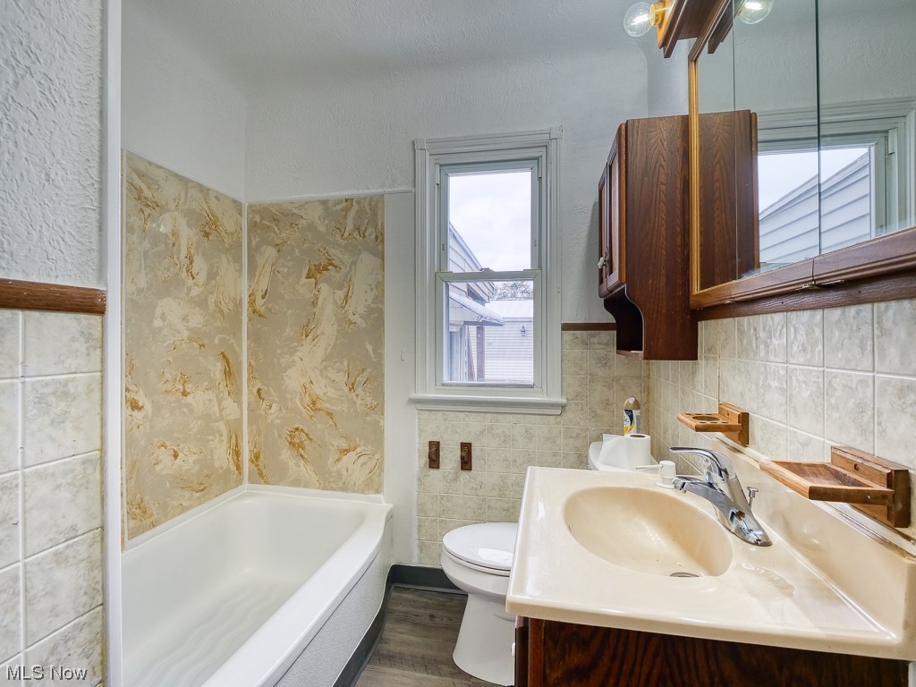 3774 Highland Road Cleveland, OH 44111 - Photo 15 of 31 Full bathroom with tile walls, toilet, hardwood / wood-style flooring, and a healthy amount of sunlight