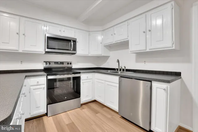 a kitchen with white cabinets stainless steel appliances and sink