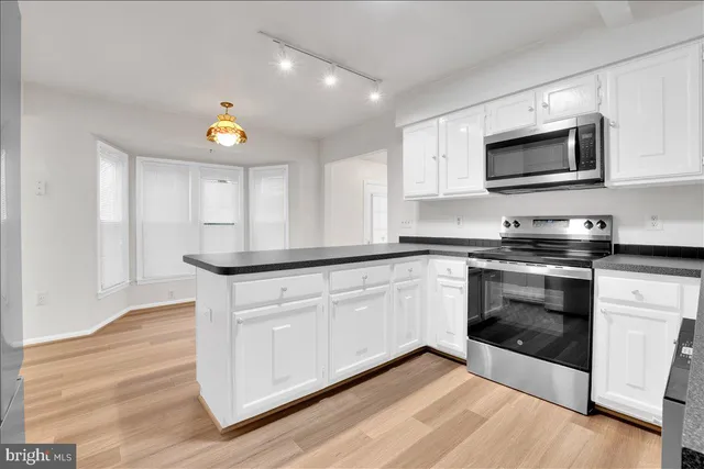 a kitchen with stainless steel appliances white cabinets and wooden floor