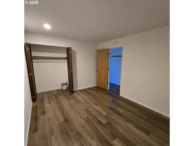 a view of an empty room with wooden floor and closet