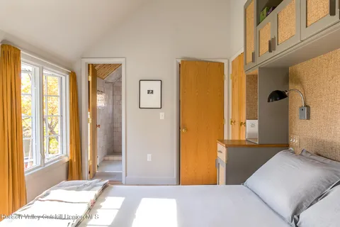 a bedroom with a bed and wooden floor next to a window