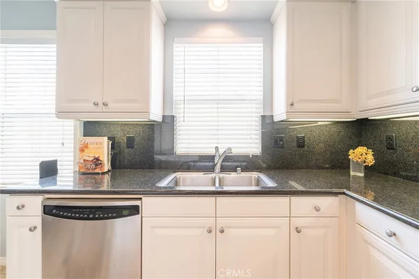 a kitchen with granite countertop a sink a stove cabinets and a window