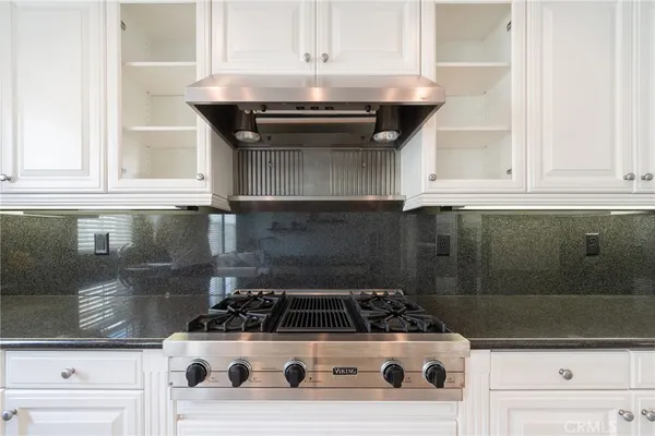 a kitchen with stainless steel appliances granite countertop a stove a sink a microwave a refrigerator and white cabinets