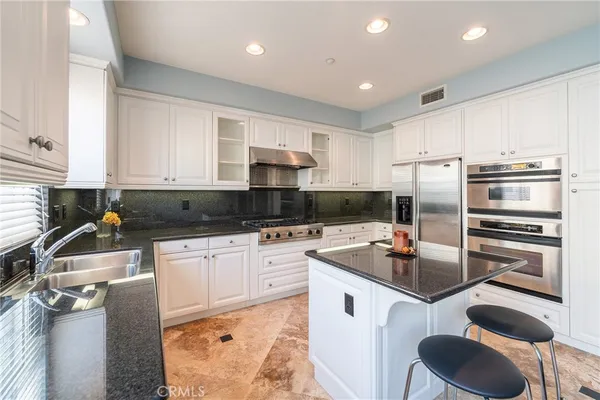 a kitchen with stainless steel appliances a stove a refrigerator and a sink
