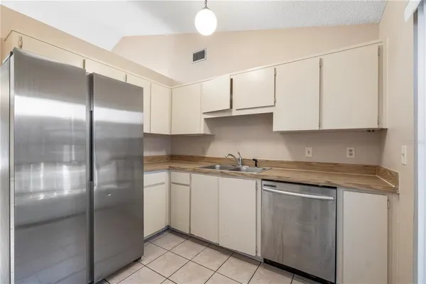 a kitchen with stainless steel appliances granite countertop a refrigerator a sink and white cabinets
