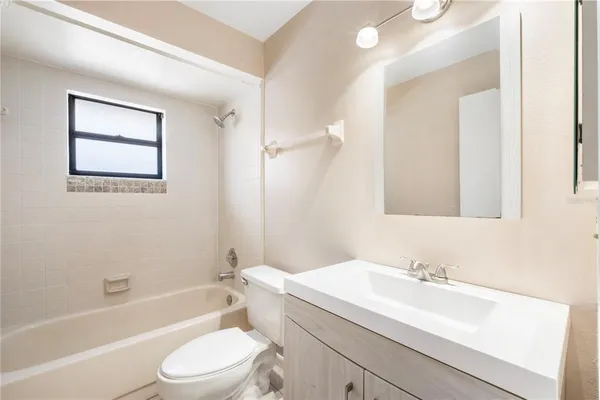 a bathroom with a toilet a sink a mirror a bathtub and vanity