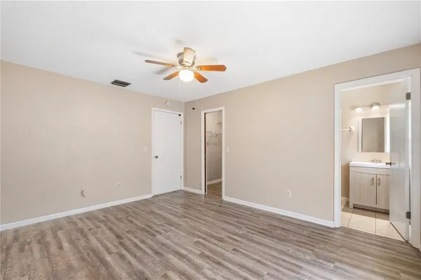 an empty room with wooden floor chandelier fan and windows