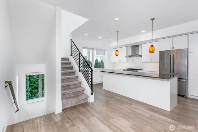 a kitchen with stainless steel appliances granite countertop a refrigerator a sink dishwasher a oven with white cabinets and wooden floor