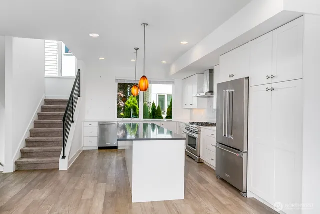 a kitchen with stainless steel appliances granite countertop a sink a stove and a wooden floors