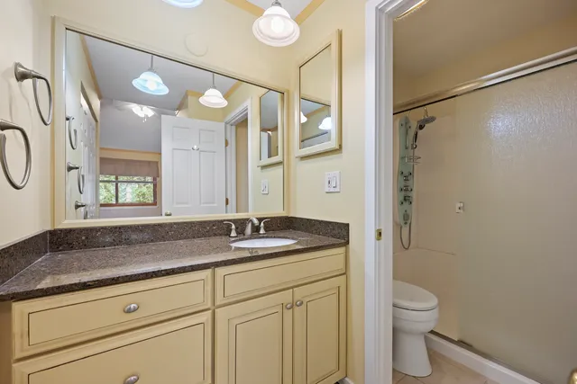a bathroom with a granite countertop sink a toilet and a mirror