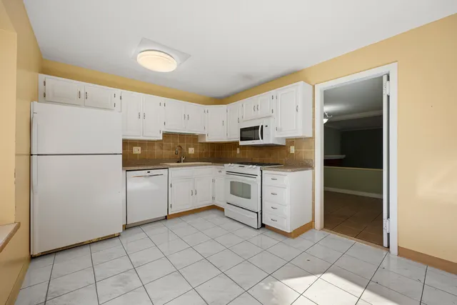 a kitchen with white cabinets and white appliances