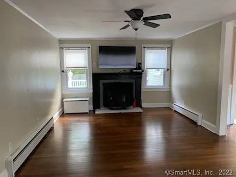 an empty room with wooden floor fireplace and windows