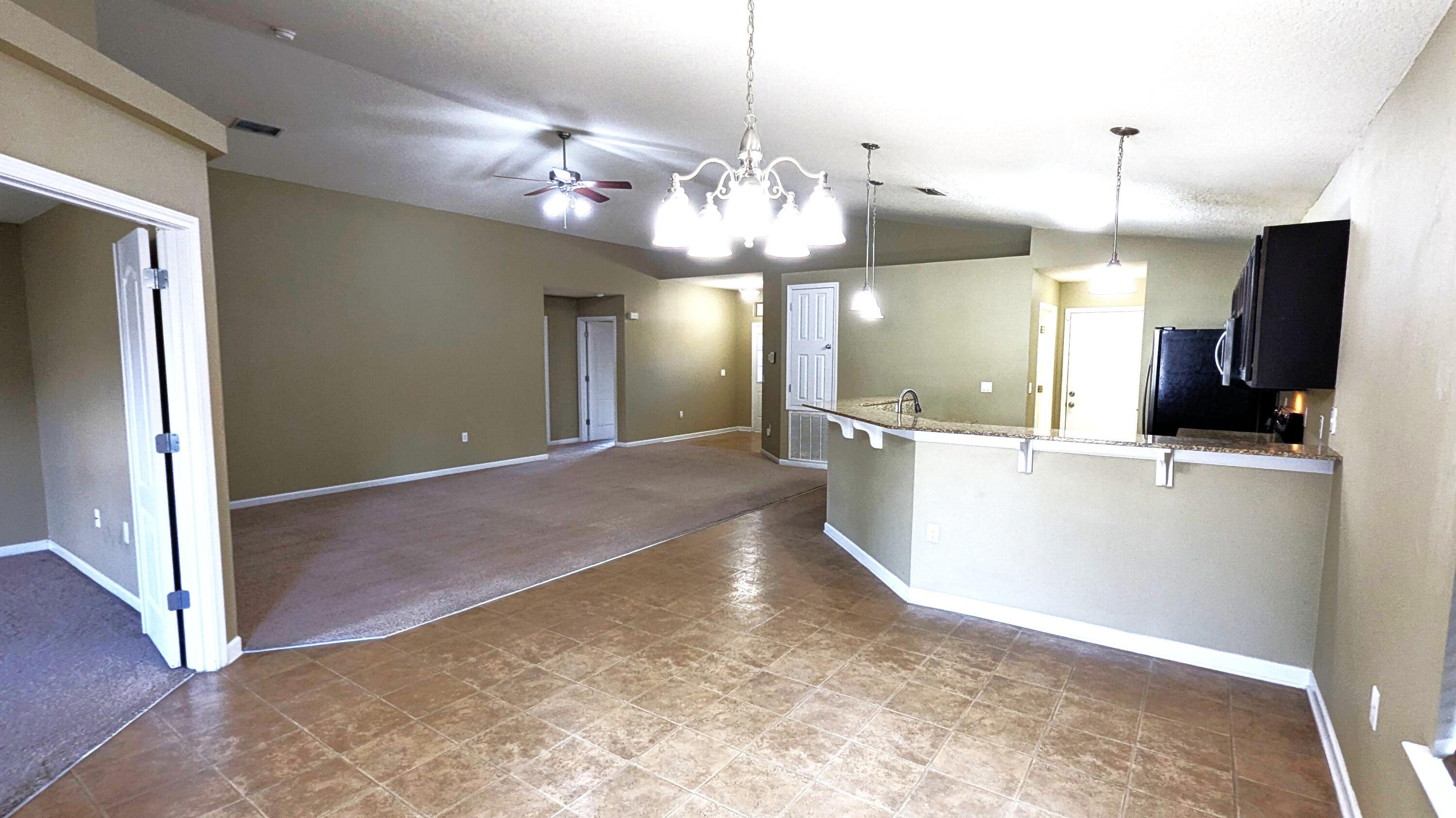 7976 Promise Creek Road Navarre, FL 32566 - Photo 11 of 29 a view of a big room with chandelier and kitchen view