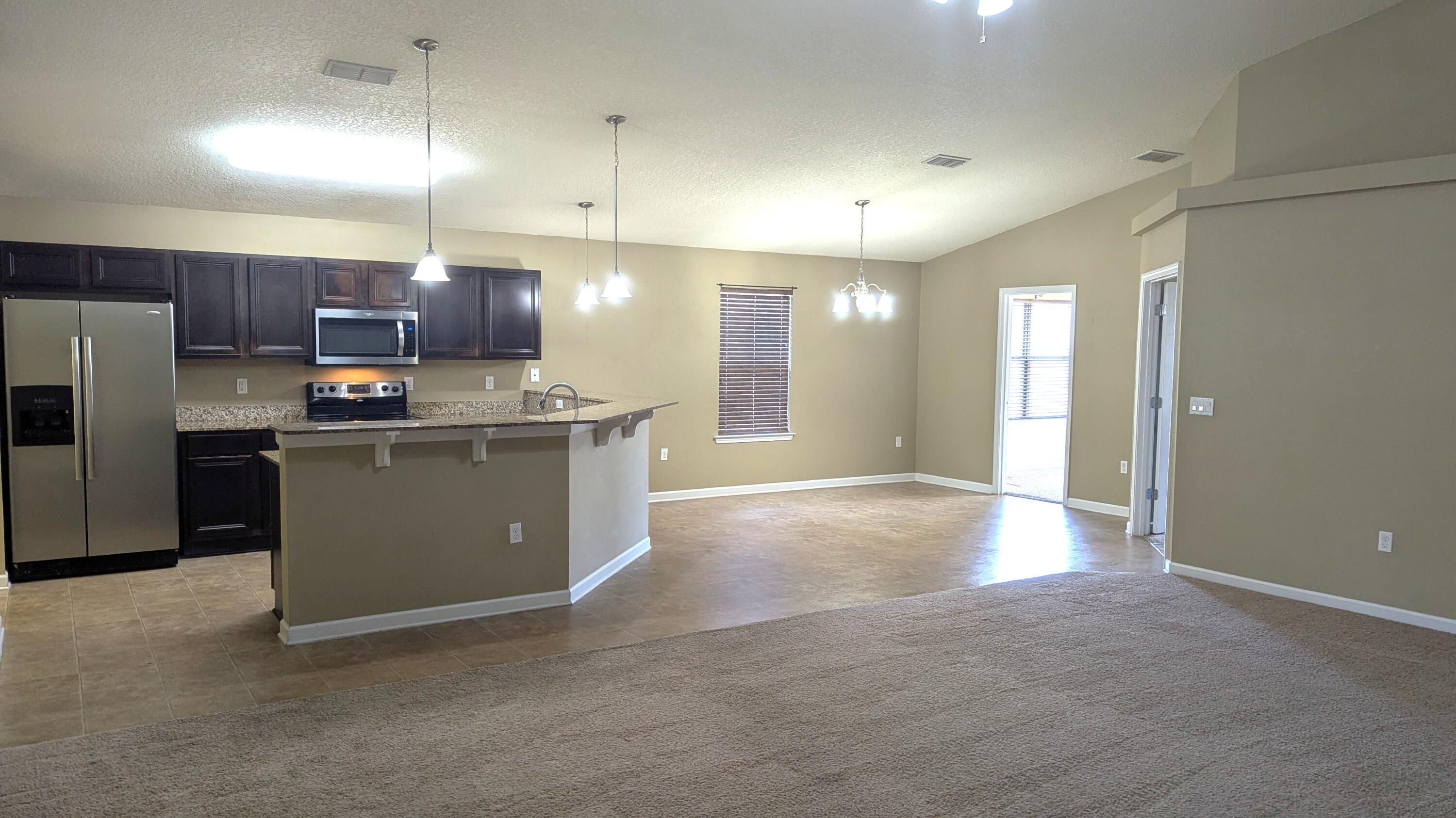 7976 Promise Creek Road Navarre, FL 32566 - Photo 8 of 29 a kitchen with stainless steel appliances granite countertop a stove a refrigerator a sink and a refrigerator