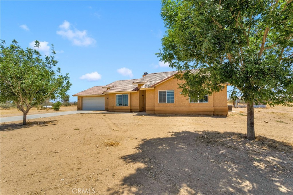 7667 Del Rosa Road Phelan, CA 92371 - Photo 1 of 1 a front view of a house with a dirt yard and a large tree