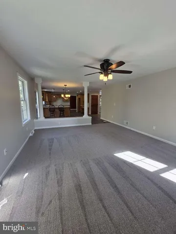 a view of an empty room with a ceiling fan and window