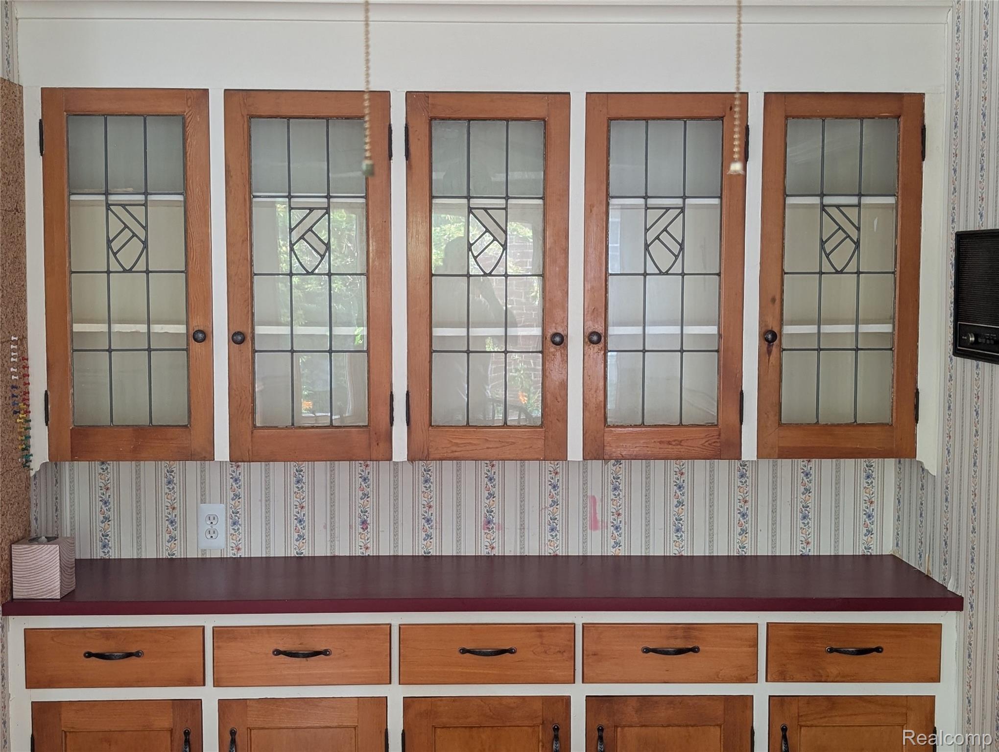 16580 Westmoreland Road Detroit, MI 48219 - Photo 11 of 37 Custom cabinetry featuring leaded glass panel doors and a red countertop