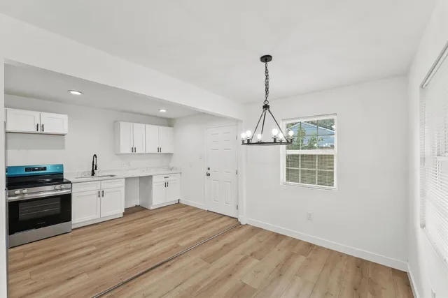 a kitchen with stainless steel appliances granite countertop a stove top oven a sink dishwasher and a wooden floor