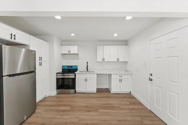 a kitchen with a refrigerator a white stove top oven and white cabinets