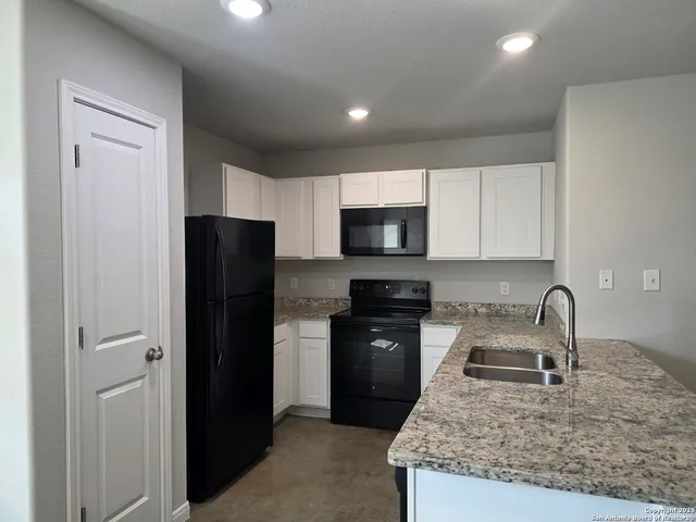 a kitchen with a sink a refrigerator and cabinets