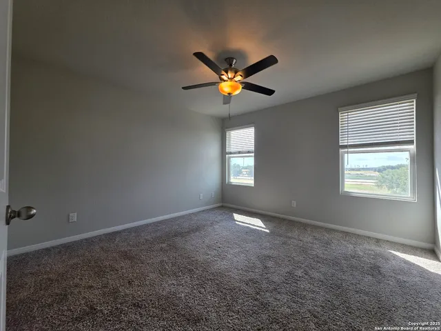 a view of an empty room with window and a ceiling fan