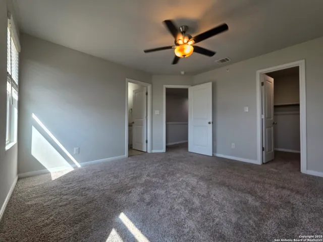 a view of an empty room with a chandelier fan