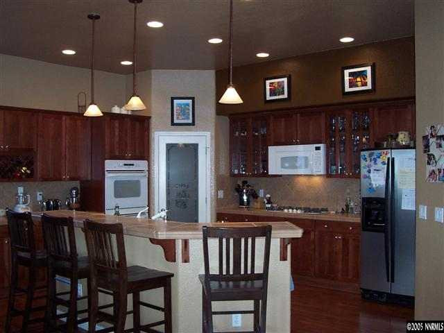 1680 Gulch Way Reno, NV 89521 - Photo 4 of 9 a kitchen with granite countertop a stove a refrigerator a sink a dining table and chairs
