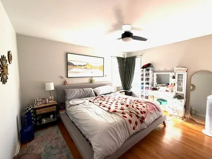 a bedroom with a bed a dresser and wooden floor